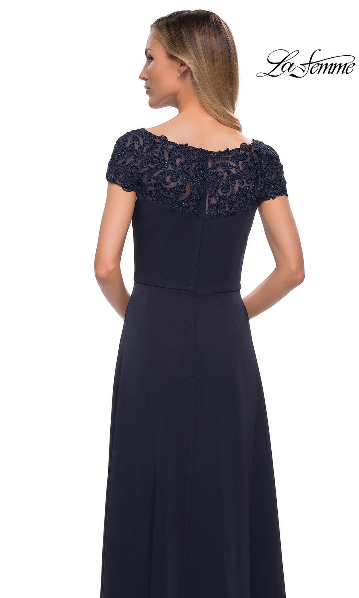 Woman wearing the Long Formal Dress: La Femme 29511 in navy blue, featuring short lace sleeves, A-line skirt, and lace back detail, standing with her back to camera.